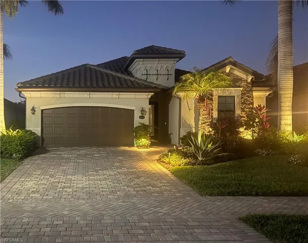 Mediterranean / spanish home with an attached garage, decorative driveway, stone siding, and stucco siding