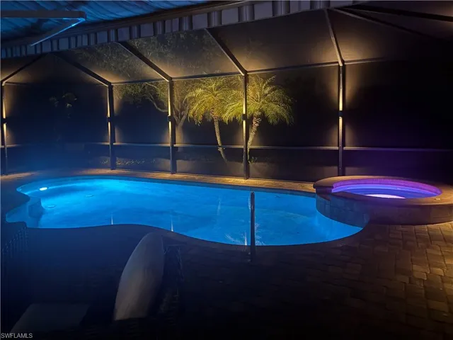 Pool at night with a pool with connected hot tub