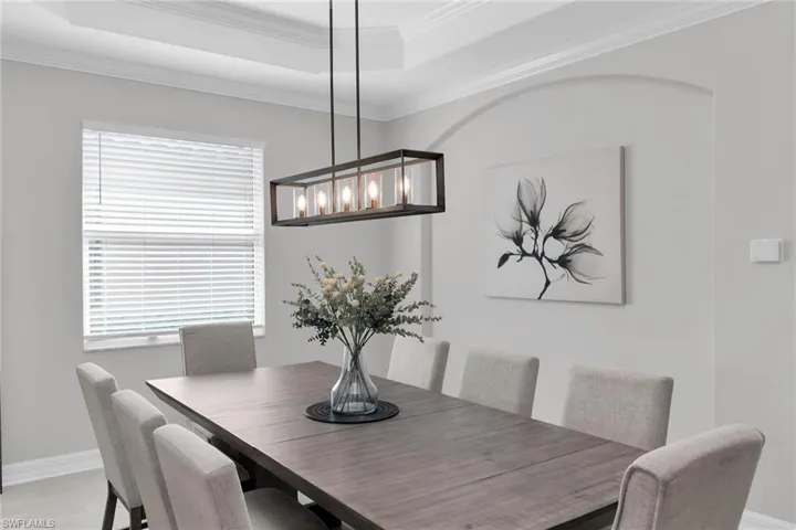 Dining room with ornamental molding, a raised ceiling, and light wood-type flooring