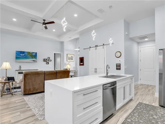 Kitchen with a barn door, white cabinets, stainless steel appliances, and decorative light fixtures