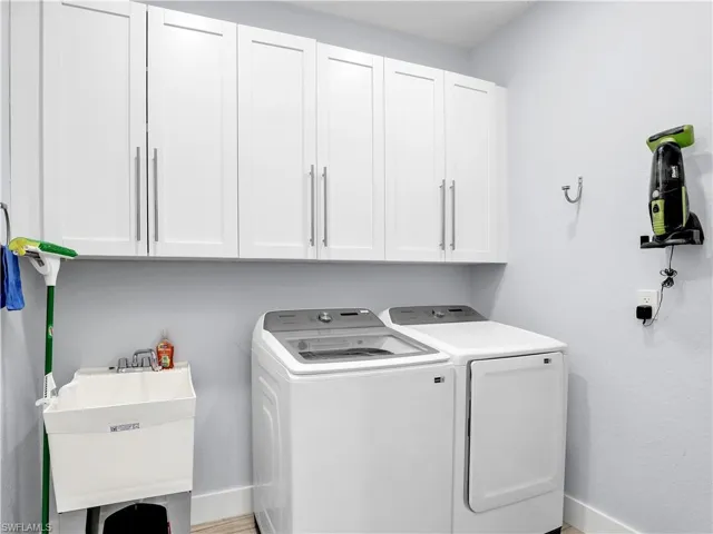 Laundry room featuring independent washer and dryer, cabinets, and sink
