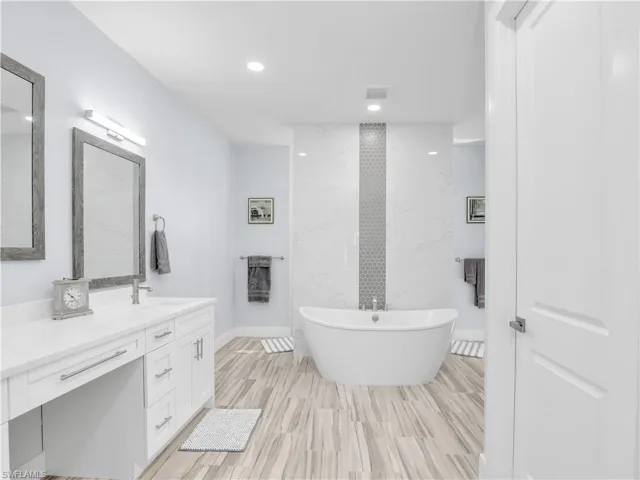 Bathroom featuring wood-type flooring, a bath, and vanity