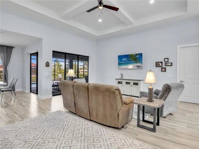 Living room with beam ceiling, ceiling fan, and light hardwood / wood-style floors