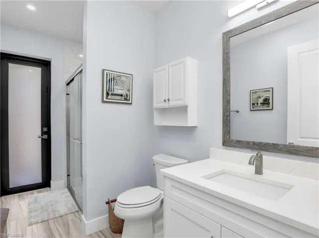 Bathroom featuring vanity, a shower with shower door, toilet, and hardwood / wood-style flooring