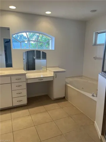 Bathroom with tile floors, a bath to relax in, and vanity