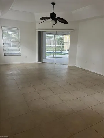 Spare room with a tray ceiling, tile flooring, and ceiling fan