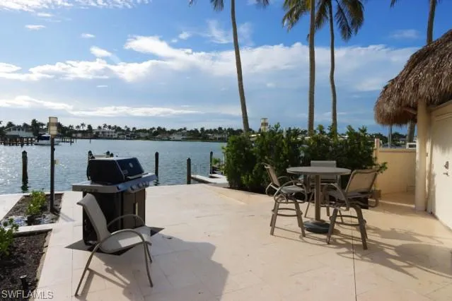 View of patio with a dock, a water view, and area for grilling