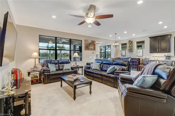 Living area with ornamental molding, a chandelier, light tile patterned flooring, recessed lighting, and a ceiling fan