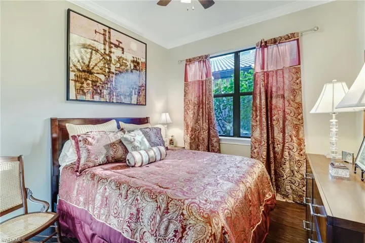 Bedroom featuring dark wood-type flooring, ornamental molding, and a ceiling fan