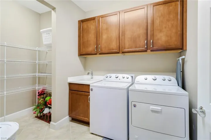 Laundry room featuring light tile patterned flooring, independent washer and dryer, and cabinet space