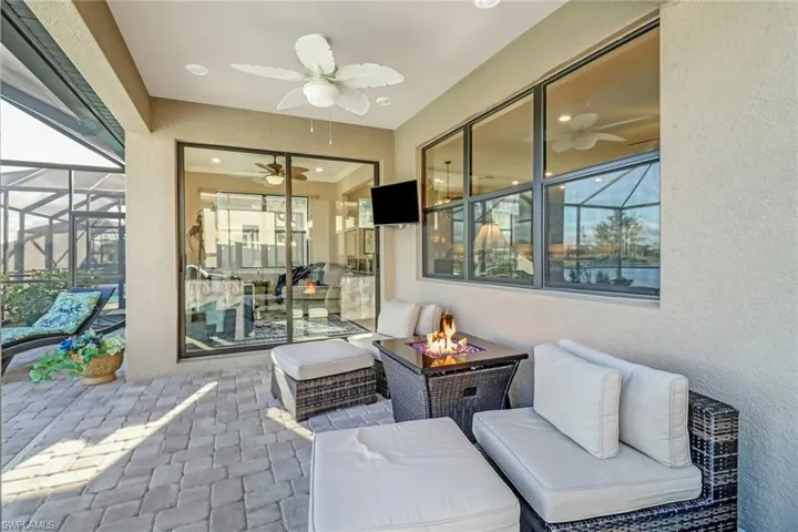 View of patio featuring a sunroom, ceiling fan, an outdoor living space with a fire pit, and a lanai