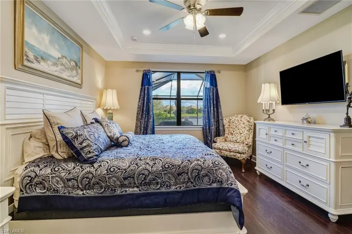 Bedroom with dark wood-type flooring, crown molding, ceiling fan, recessed lighting, and a raised ceiling