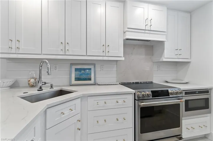 Kitchen with white cabinetry, stainless steel appliances, and tasteful backsplash