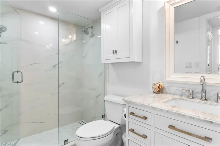Bathroom featuring toilet, vanity, and an enclosed shower