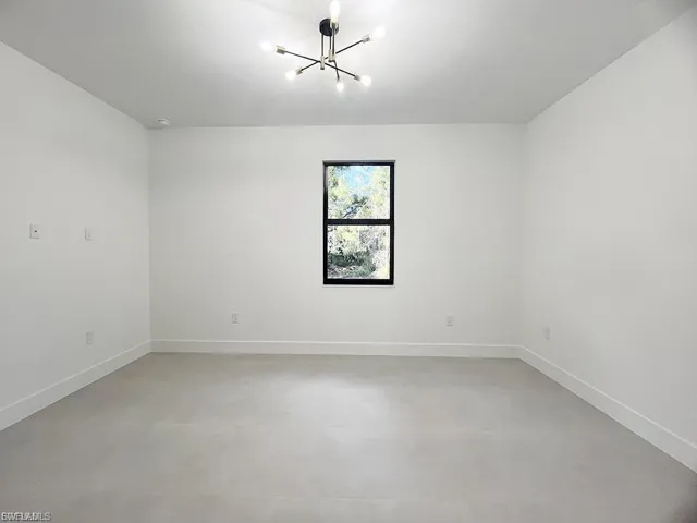 Spare room with finished concrete floors and a chandelier