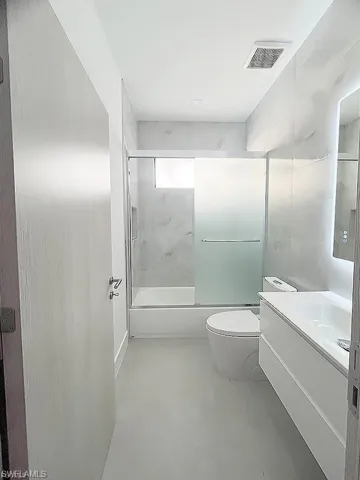 Full bathroom featuring vanity, enclosed tub / shower combo, and tile walls