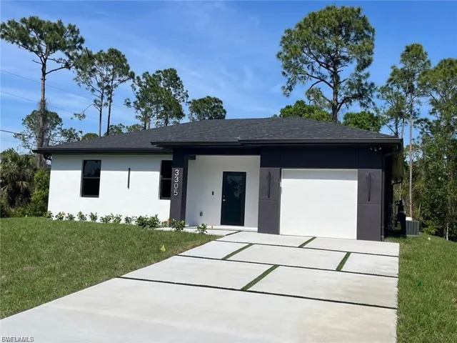 View of front of house with concrete driveway, stucco siding, an attached garage, a front lawn, and roof with shingles