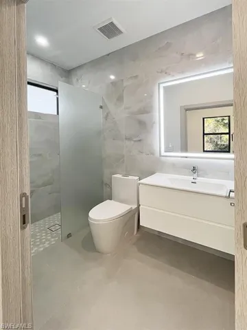 Full bathroom with tile walls, a shower stall, and vanity