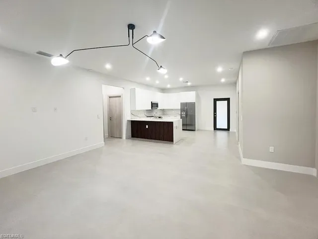 Unfurnished living room with finished concrete flooring and recessed lighting