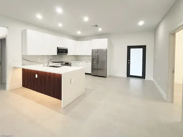 Kitchen with stainless steel appliances, recessed lighting, a peninsula, light countertops, and concrete flooring