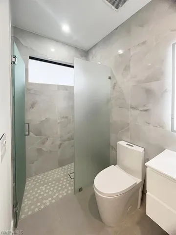 Bathroom featuring tile walls, a stall shower, and vanity