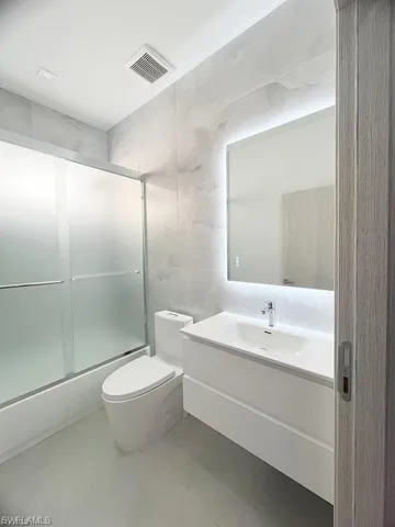 Bathroom featuring tile walls, vanity, and enclosed tub / shower combo