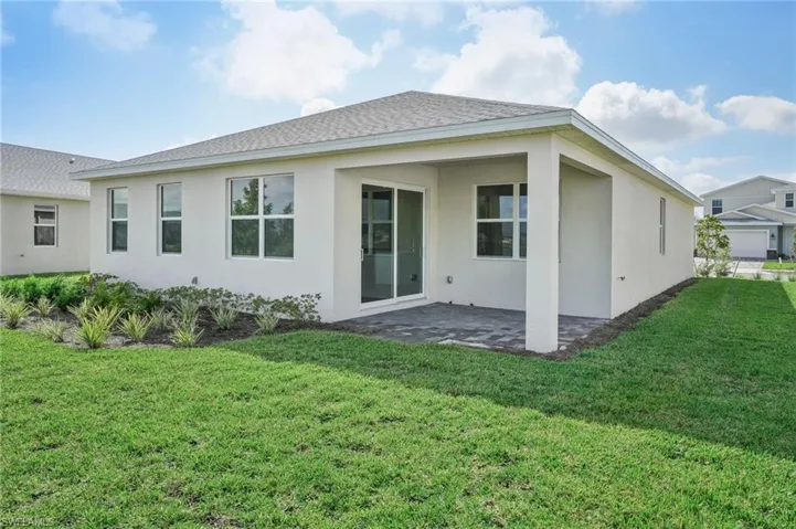 Back of property featuring a garage, a yard, and a patio area