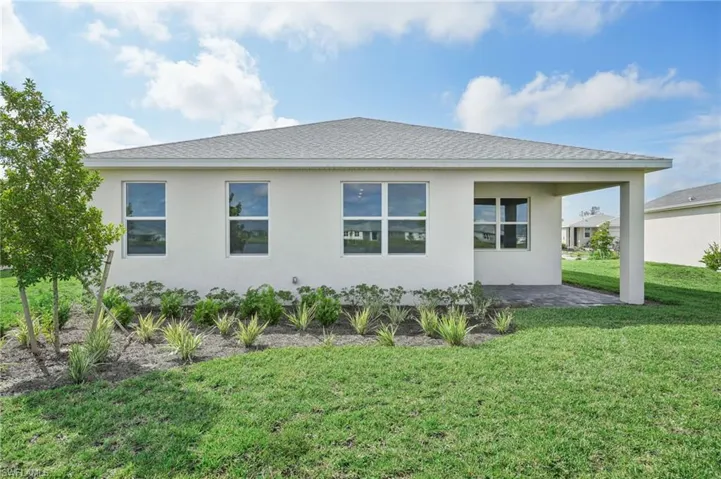 View of side of property with a lawn and a patio
