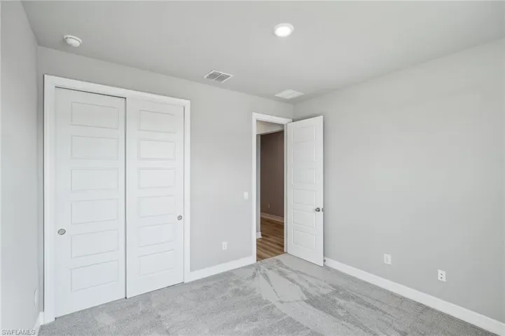 Unfurnished bedroom featuring a closet and light colored carpet
