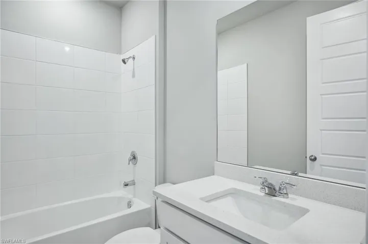 Full bathroom with vanity, tiled shower / bath combo, and toilet