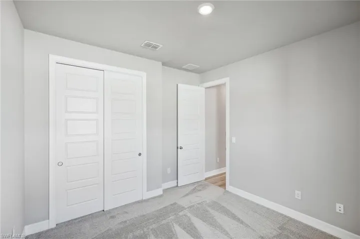 Unfurnished bedroom featuring light colored carpet and a closet