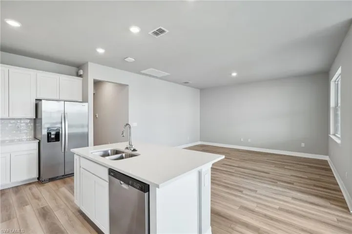 Kitchen featuring white cabinets, a center island with sink, stainless steel appliances, and sink