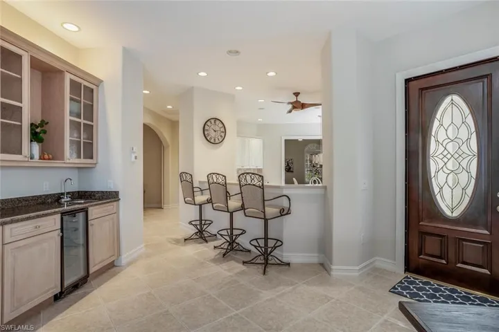 Entrance foyer with light tile patterned floors, wet bar, and beverage cooler