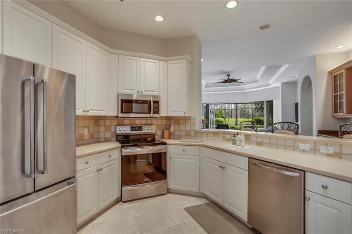 Kitchen featuring sink, white cabinetry, tasteful backsplash, appliances with stainless steel finishes, and a raised ceiling