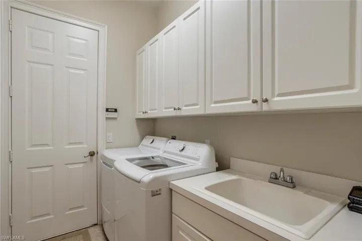 Laundry area featuring sink, washing machine and dryer, and cabinets