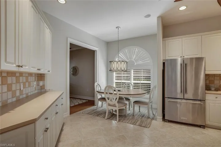 Kitchen with high end fridge, hanging light fixtures, white cabinetry, and light tile patterned floors