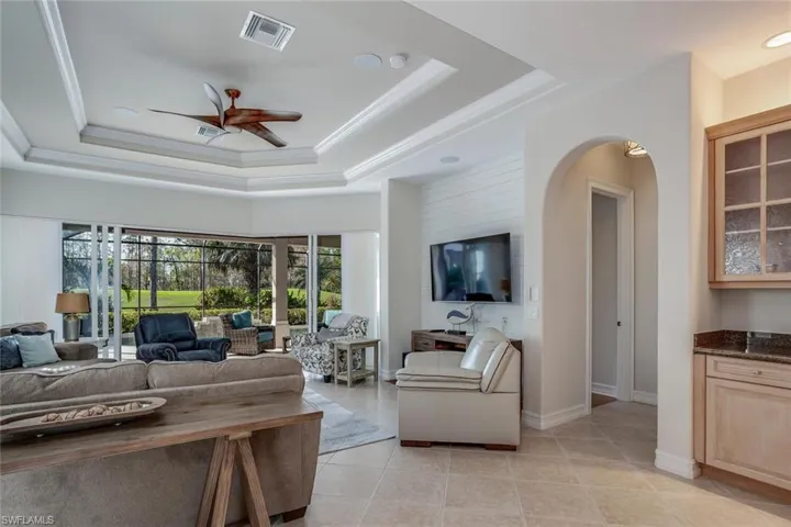 Great Room featuring light tile floors, a tray ceiling w/ crown molding, and ceiling fan