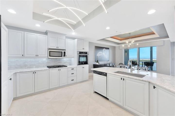 The beautiful kitchen boasts recently painted wood cabinets finished in a light grey, quartz countertops, tile backsplash, and a GAS cooktop.