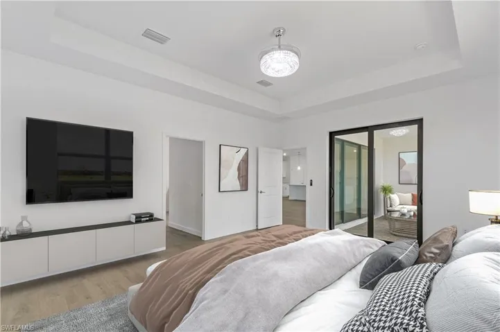 Bedroom with a tray ceiling, a chandelier, and wood style flooring