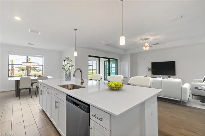 Kitchen featuring dishwasher, plenty of natural light, an island with sink, and pendant lighting