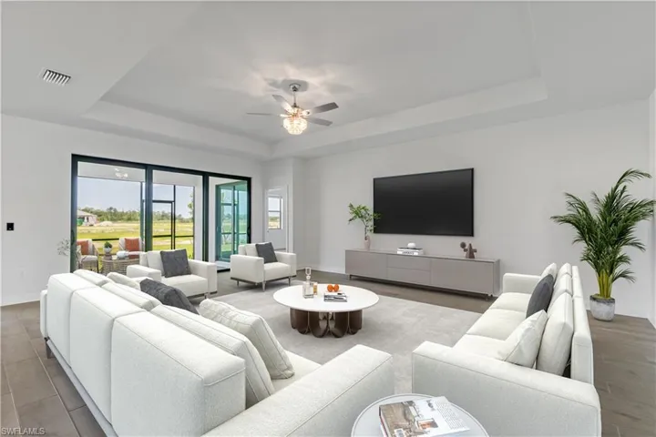 Living room featuring ceiling fan and a raised ceiling