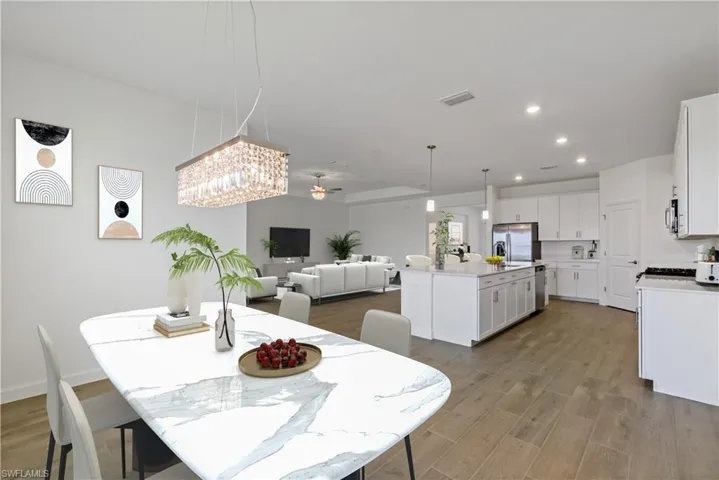 Dining space featuring wood-style flooring and ceiling fan with notable chandelier