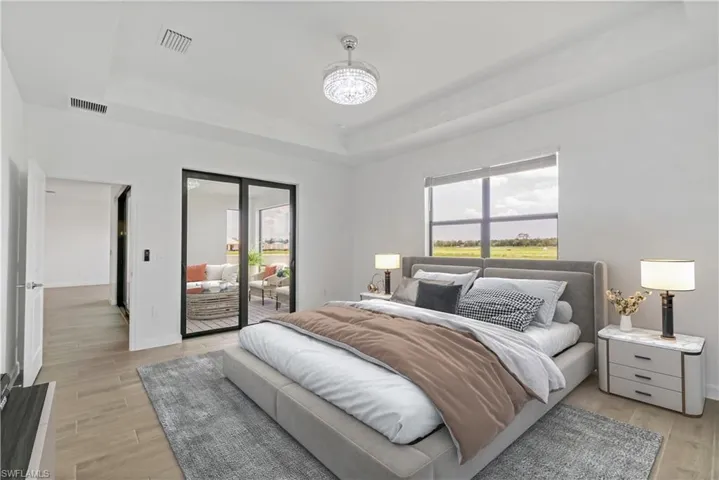 Bedroom with an inviting chandelier, a tray ceiling, access to outside, and wood style flooring