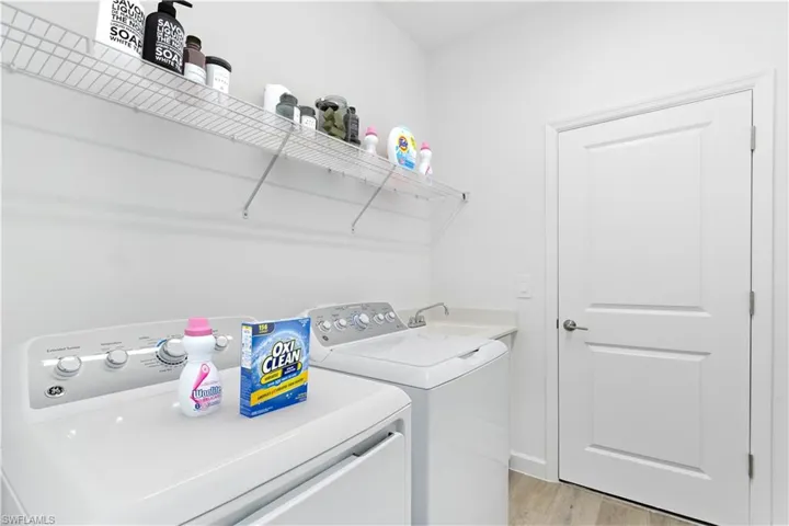 Laundry area with independent washer and dryer, sink and wood style flooring