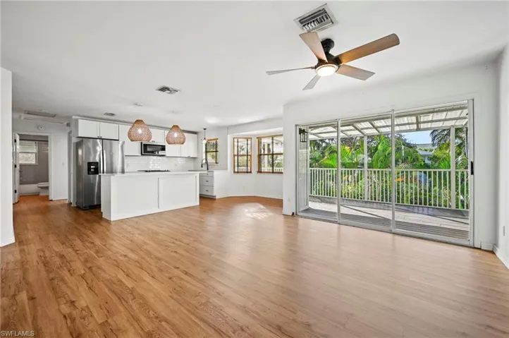 Unfurnished living room with healthy amount of natural light, a ceiling fan, and light wood-style floors