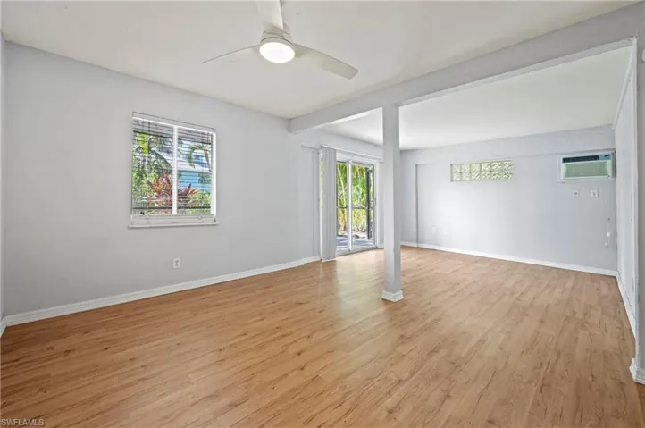 Empty room with light wood finished floors, healthy amount of natural light, a ceiling fan, and an AC wall unit