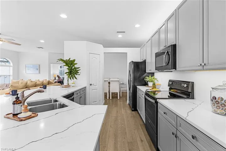 Kitchen featuring electric range, gray cabinets, light stone countertops, light wood-type flooring, and recessed lighting