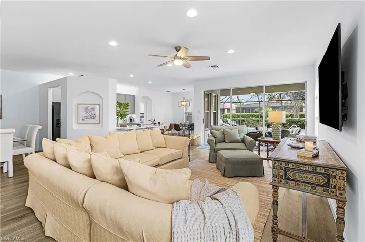 Living room featuring recessed lighting, light wood-type flooring, a sunroom, arched walkways, and a ceiling fan
