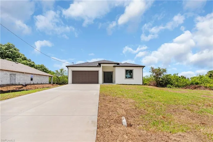 Prairie-style home with an attached garage, concrete driveway, stucco siding, and a front lawn