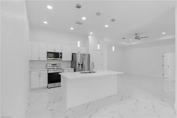 Kitchen with light marble finish floors, appliances with stainless steel finishes, white cabinets, and recessed lighting